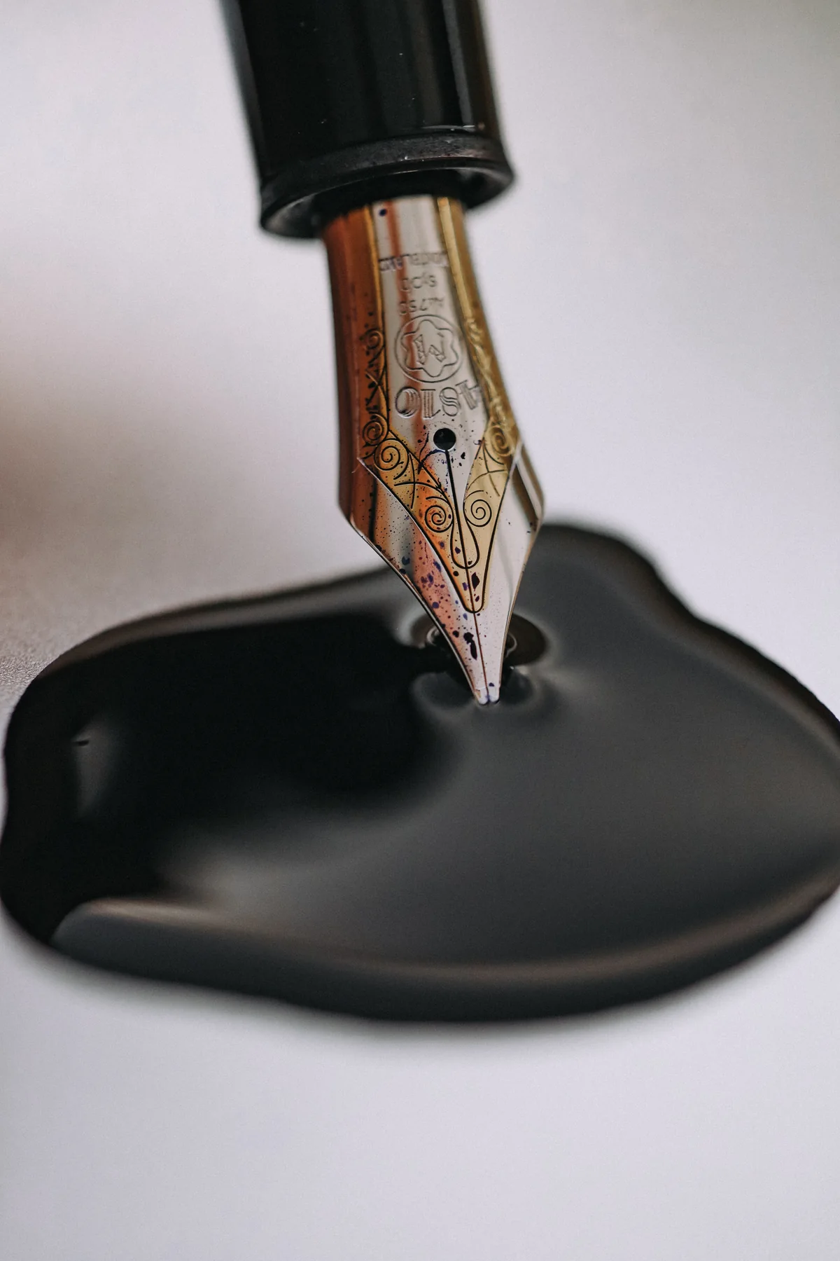 Close-up of a fountain pen nib touching black ink