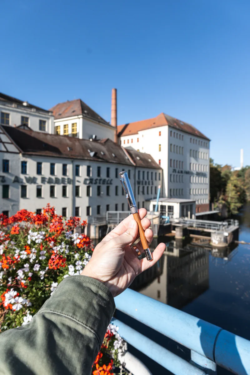 A Graf von Faber-Castell Perfect Pencil held in front of the historic factory.