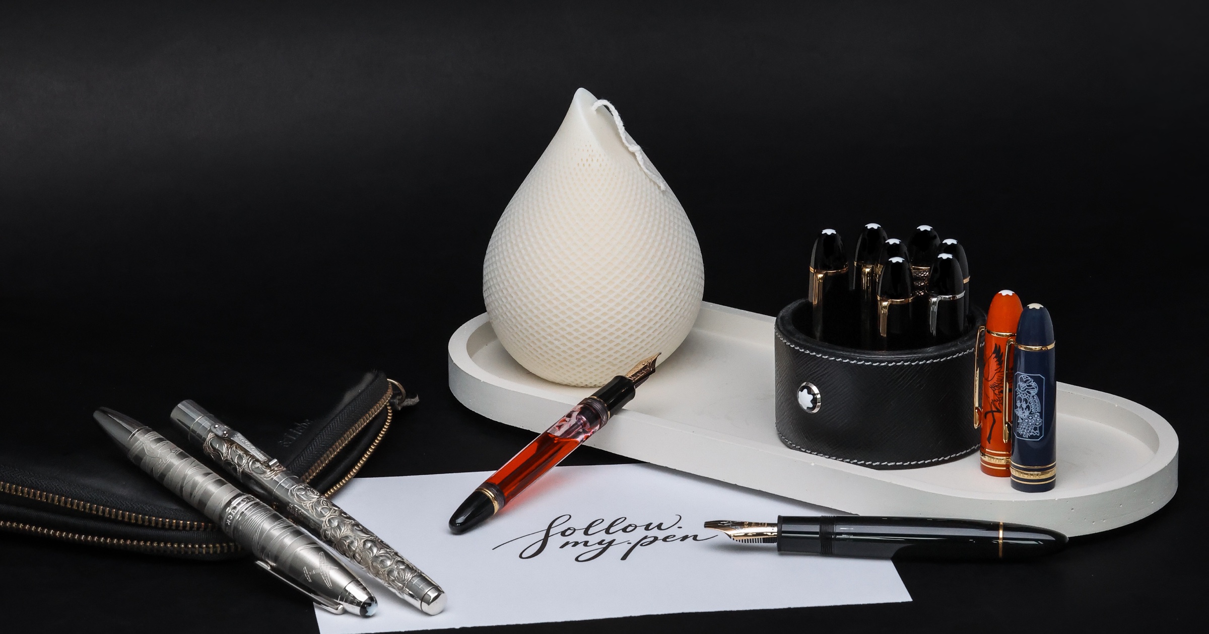 Luxury fountain pen collection arranged on a black writing desk