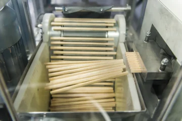 Unpainted wooden pencils emerging from a shaping machine at Faber-Castell.