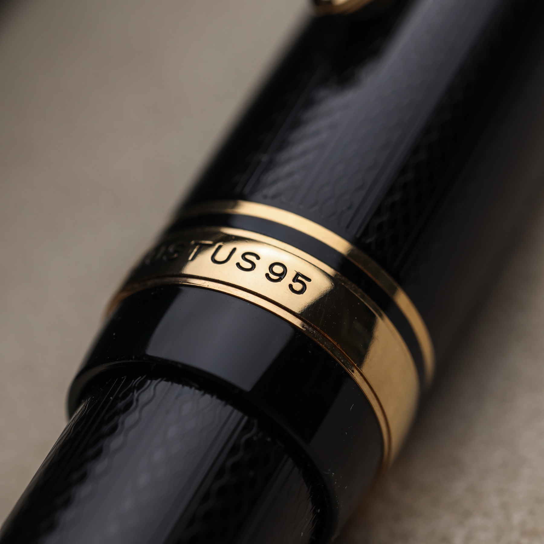 Macro detail of the gold Justus 95 name ring and engraved black resin