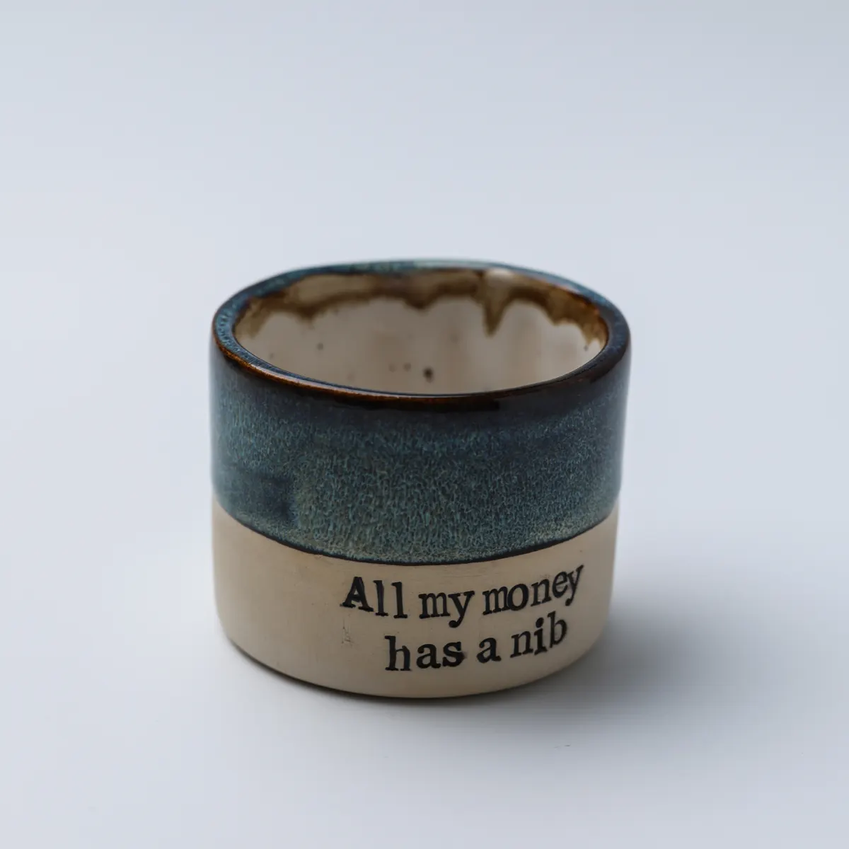 All My Money Has a Nib ceramic mug viewed from above, showing its speckled cream interior