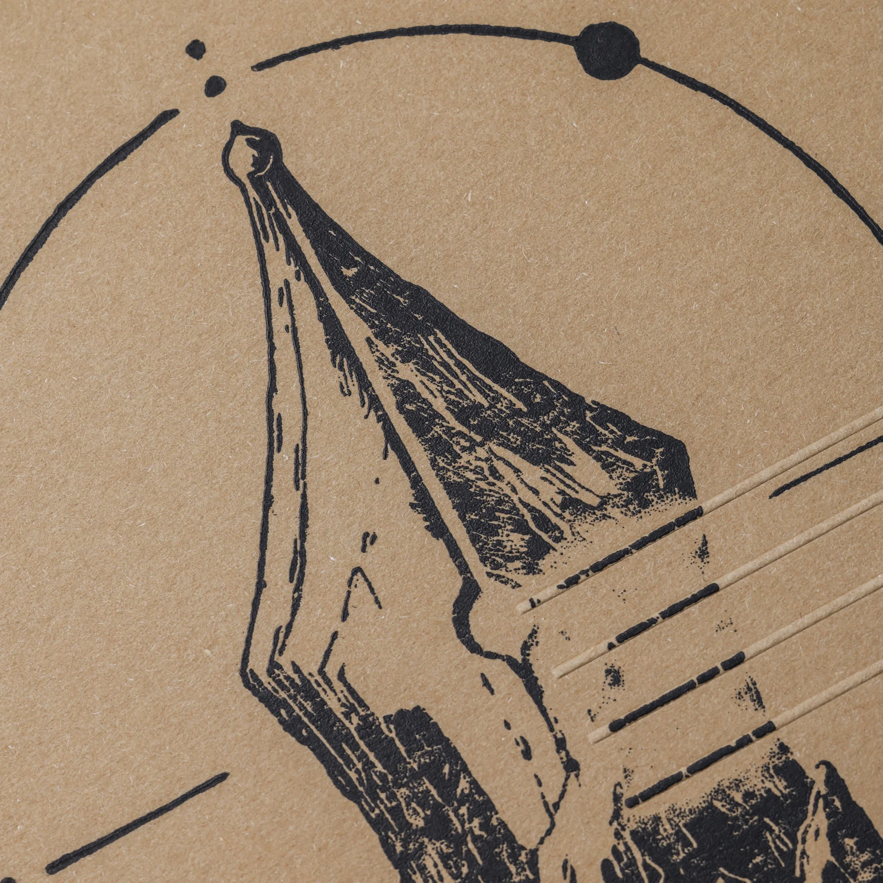 Close-up of the linocut nib tip, circular motif and natural paper texture on the ASCENT notebook cover