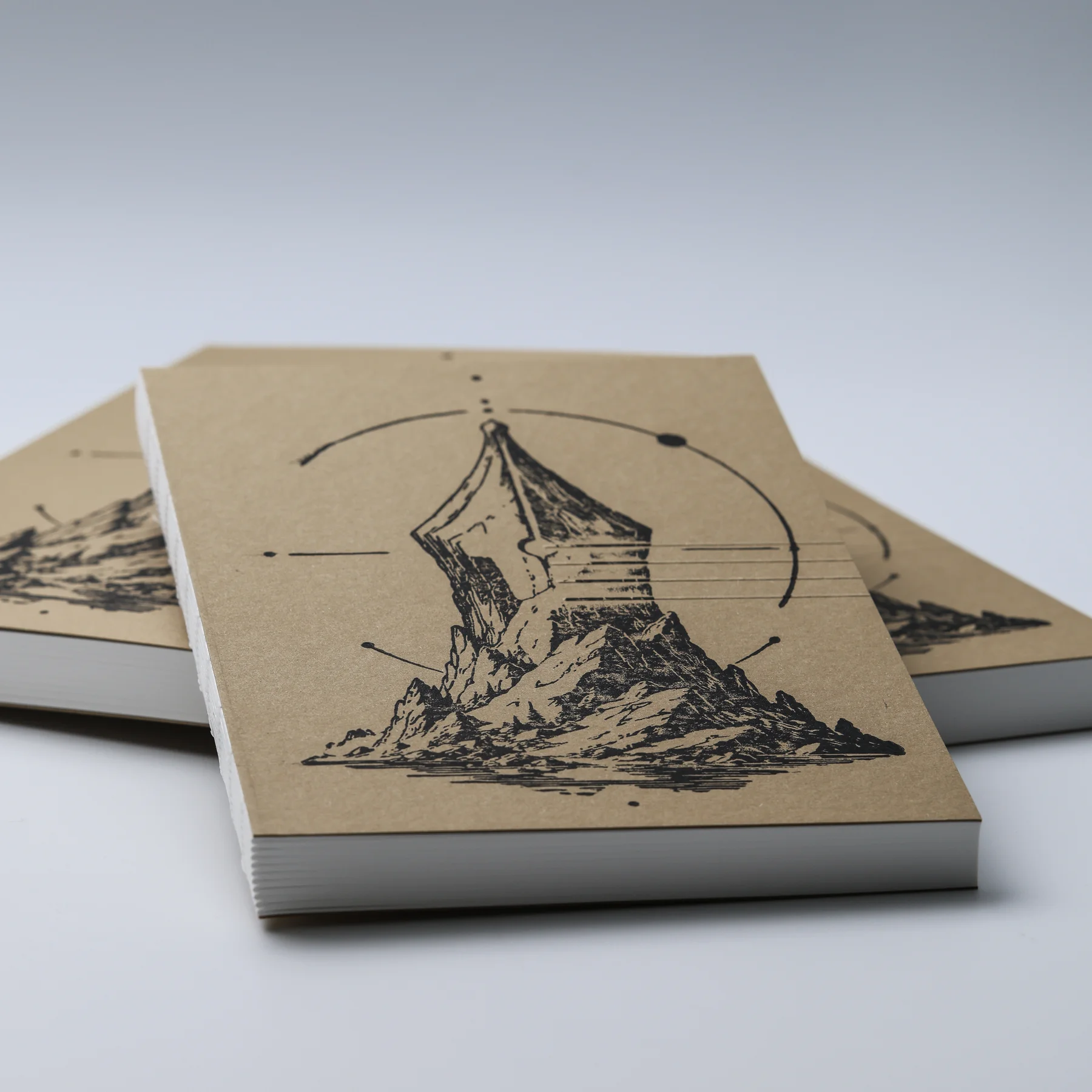 Low-angle view of three FMP Notebook No.1 ASCENT notebooks showing the linocut covers and white page edges