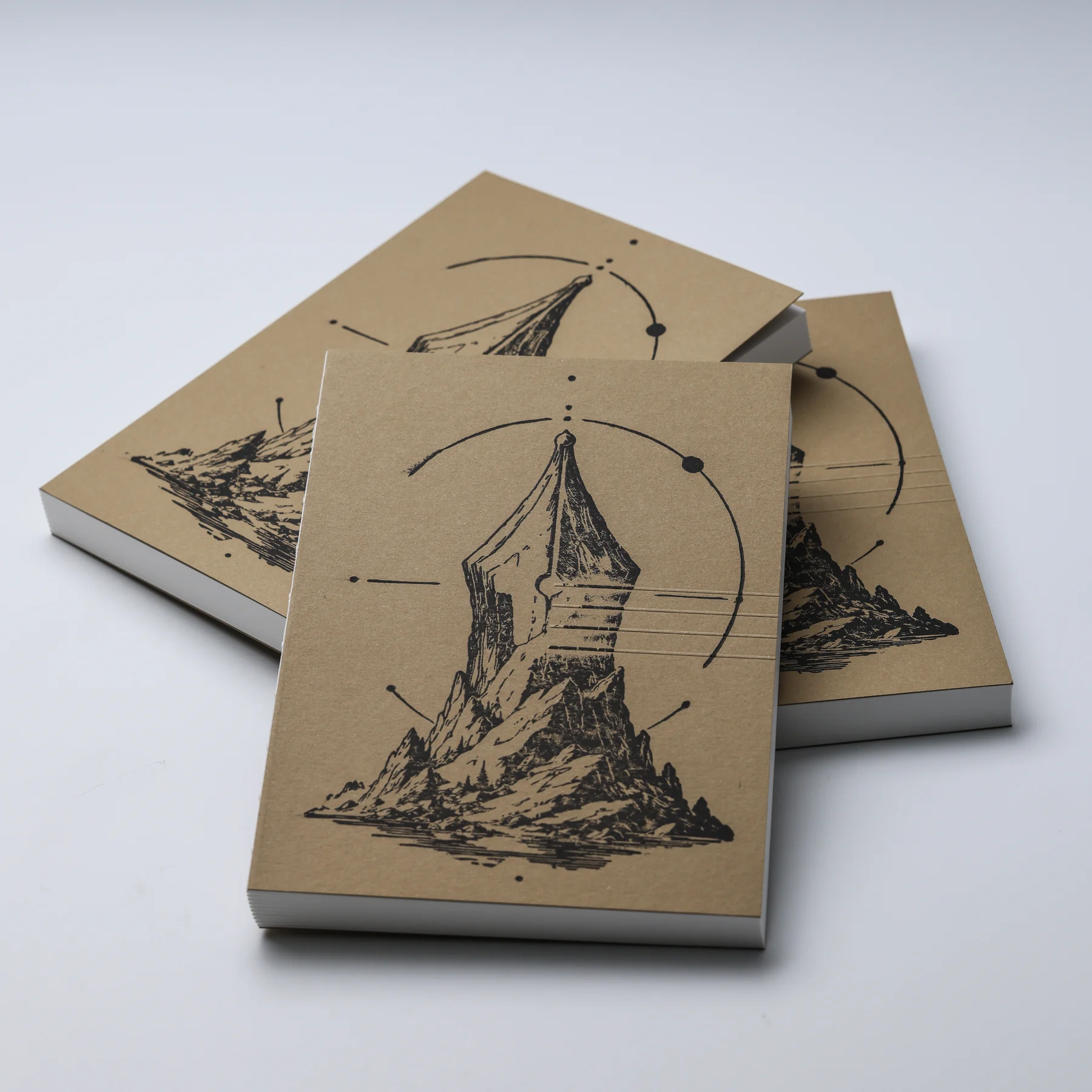 Three FMP Notebook No.1 ASCENT notebooks arranged with their natural paper covers and black nib-and-mountain artwork visible