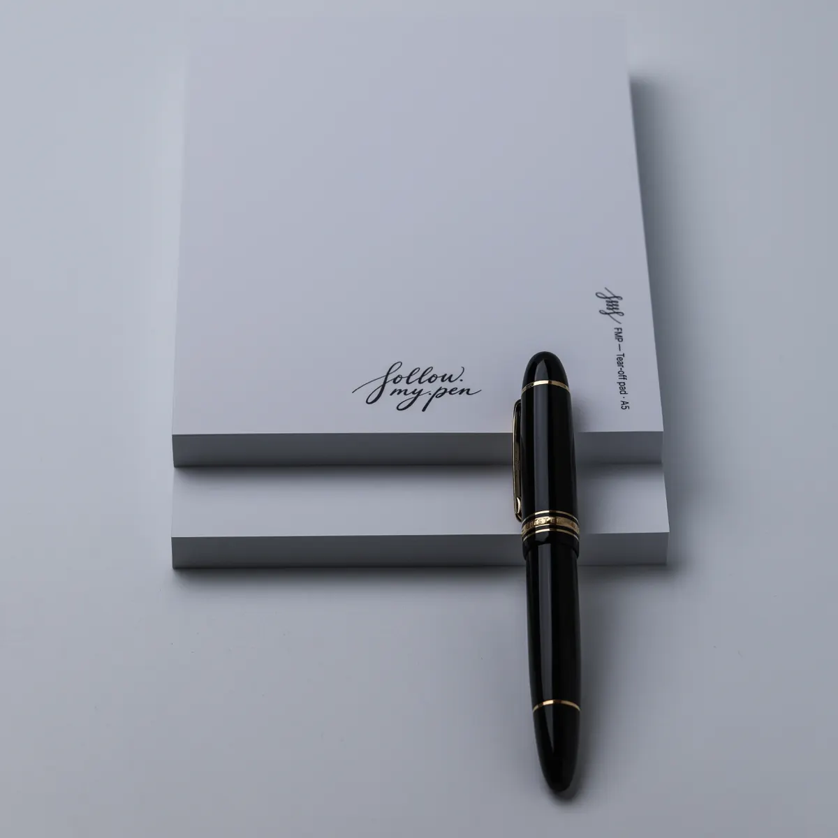 Two stacked FMP A5 tear-off pads with a capped black and gold fountain pen alongside
