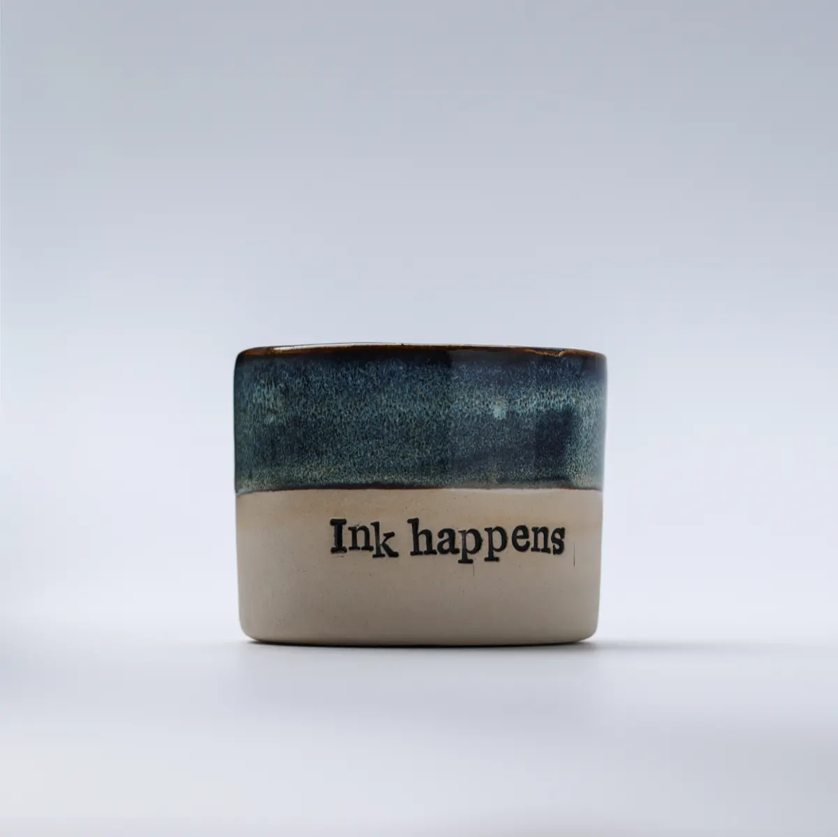 Straight-on view of the Ink Happens lettering and textured blue glaze
