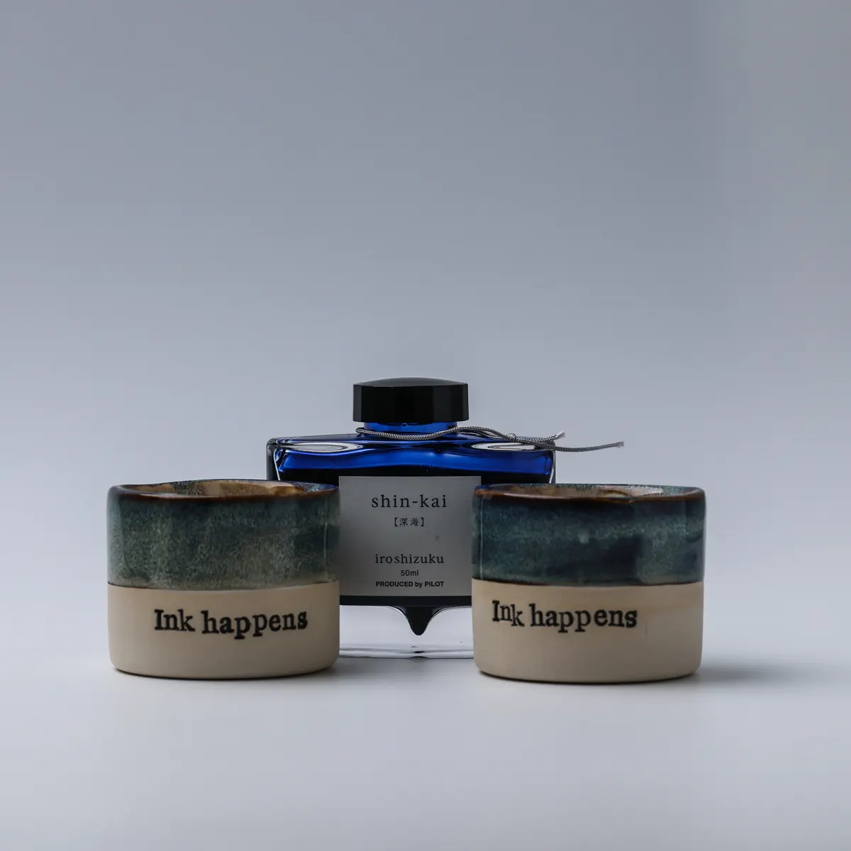 Two handmade Ink Happens mugs in front of a Pilot Iroshizuku Shin-kai ink bottle