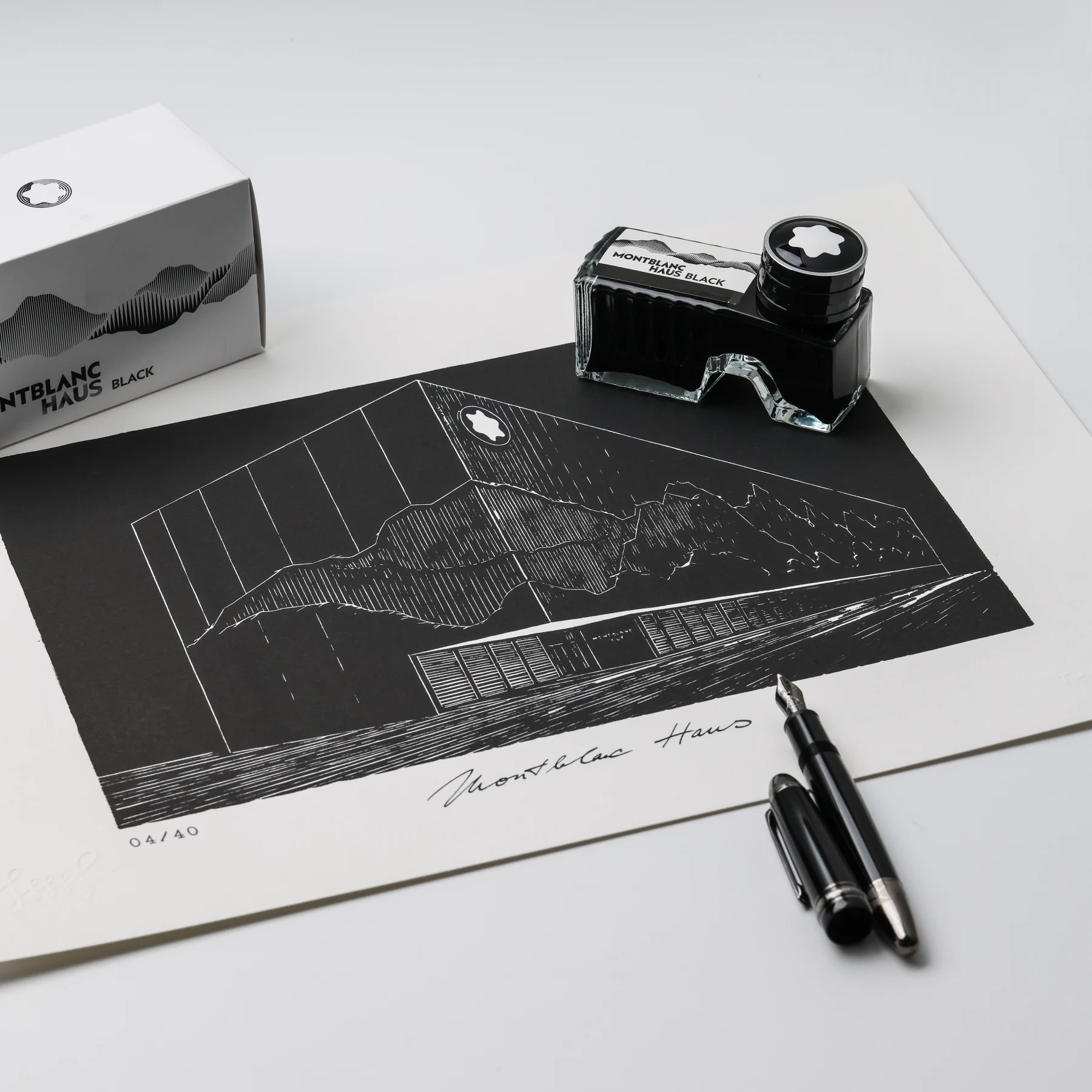 Angled view of the Montblanc Haus Hamburg linocut beside a black ink bottle and fountain pen