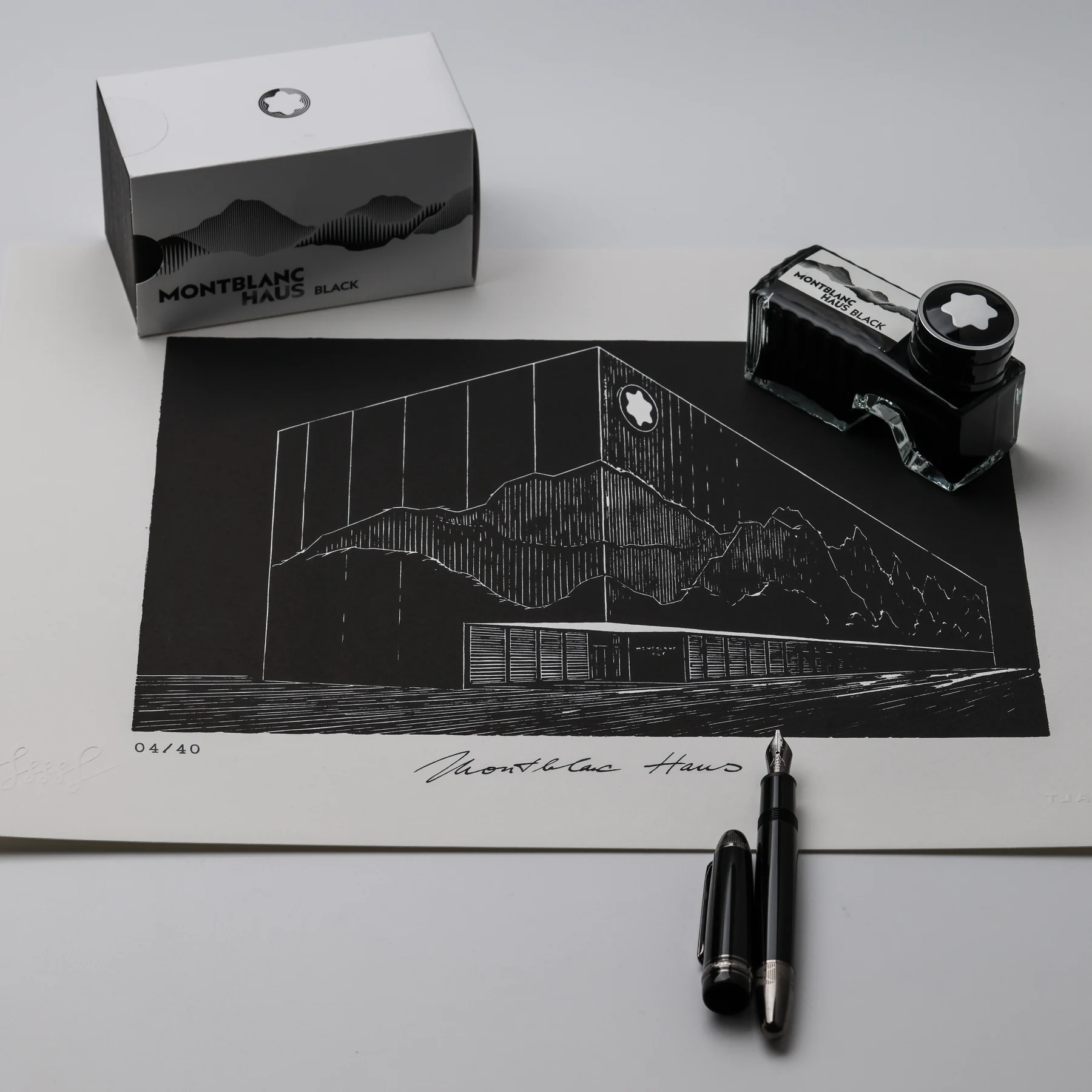 Montblanc Haus print arranged on a desk with Haus Black ink, its packaging and a fountain pen